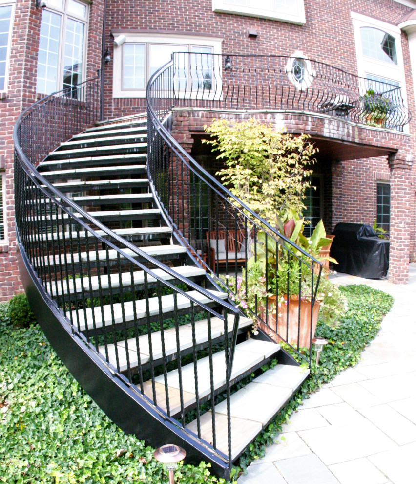 Large traditional curved metal railing staircase in Detroit with slate treads and metal risers.