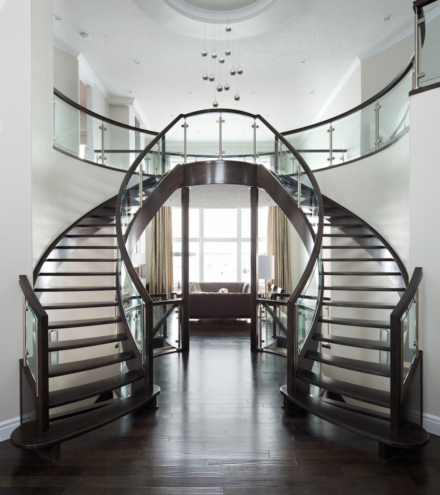 Cette photo montre un escalier sans contremarche courbe moderne avec des marches en bois, un garde-corps en verre et éclairage.