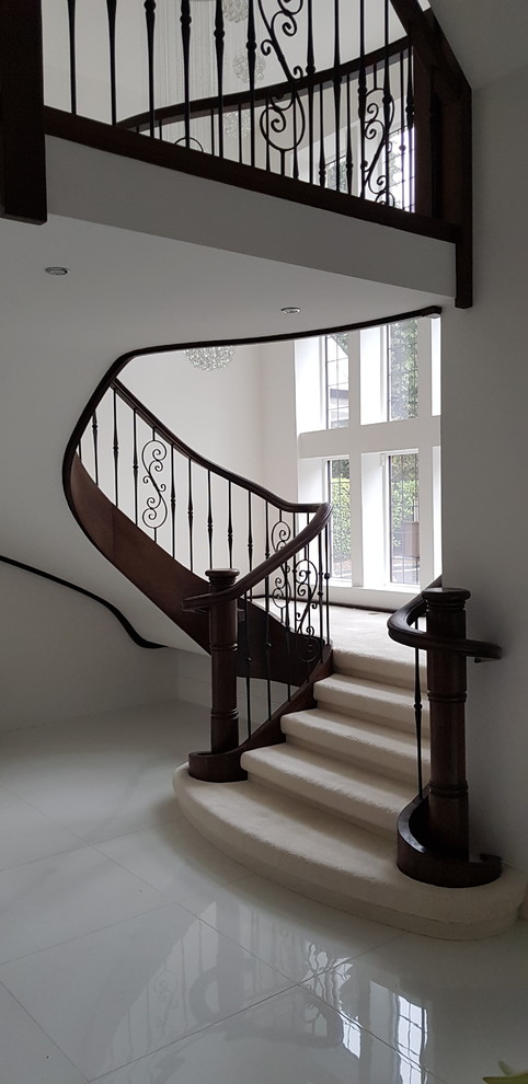 Modelo de escalera curva clásica grande con escalones de madera, contrahuellas de madera y barandilla de metal