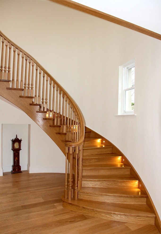 Diseño de escalera curva tradicional grande con escalones de madera y contrahuellas de madera