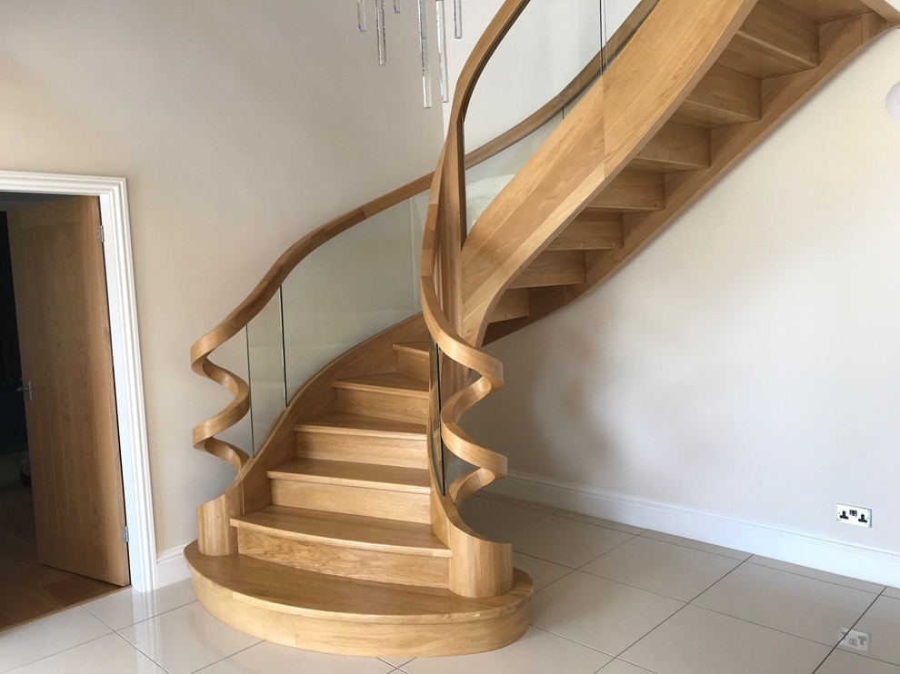 Photo of a large contemporary wood curved glass railing staircase in Other with wood risers.