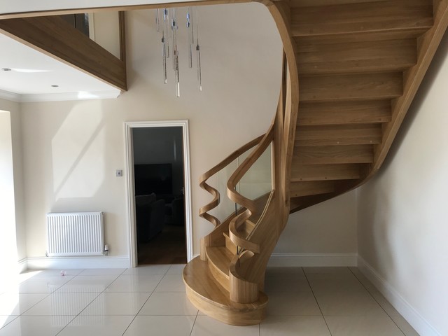 Curved Oak stairs with a roller coaster handrails Contemporary