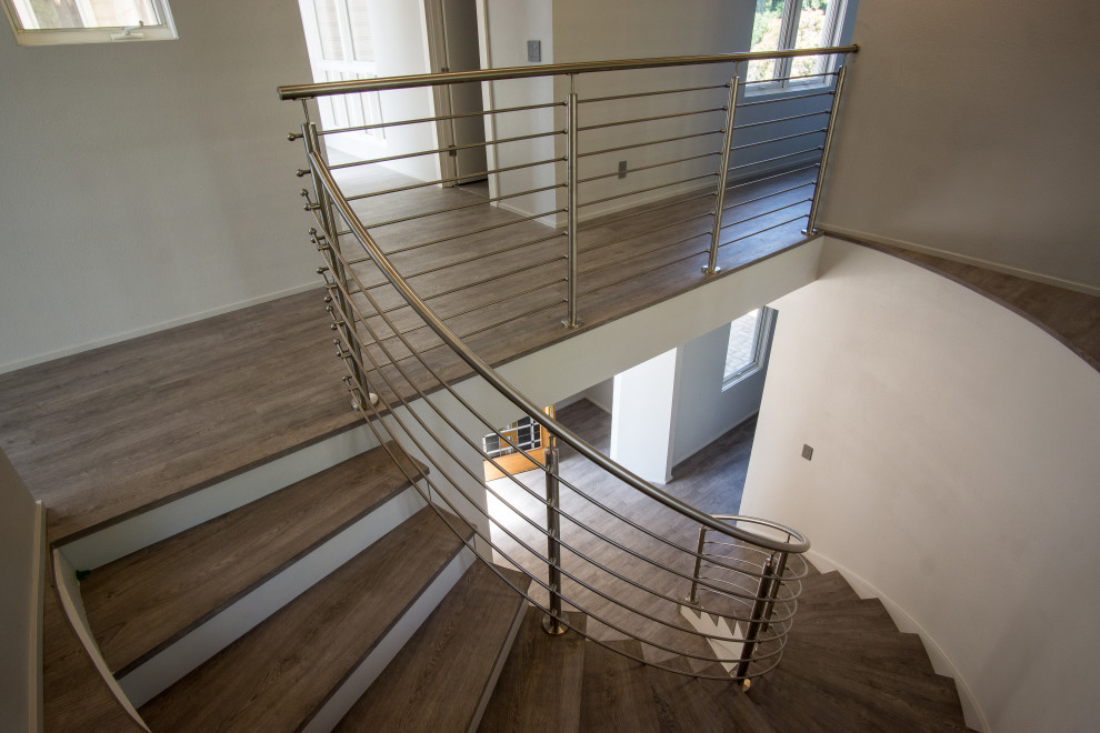 Gewendelte, Mittelgroße Moderne Holztreppe mit gebeizten Holz-Setzstufen und Stahlgeländer in Denver
