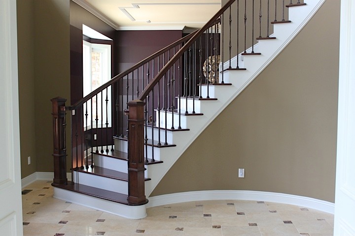 Réalisation d'un grand escalier peint courbe tradition avec des marches en bois.
