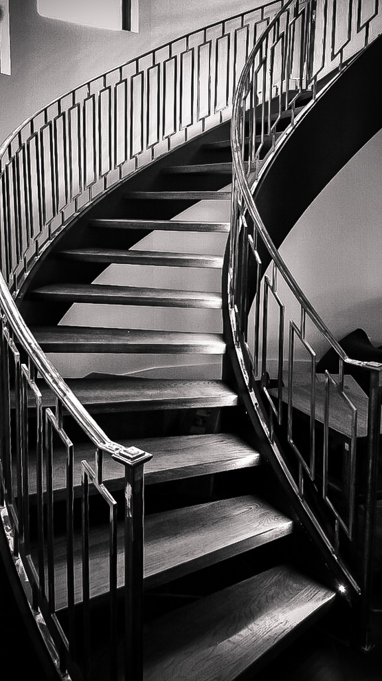 Стильный дизайн: большая изогнутая лестница в стиле модернизм с деревянными ступенями без подступенок - последний тренд