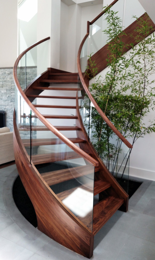 Cette photo montre un grand escalier sans contremarche courbe tendance avec des marches en bois.