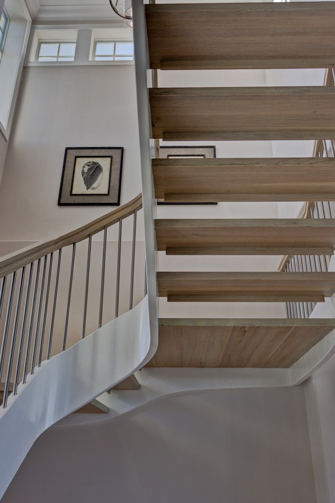 Стильный дизайн: большая изогнутая лестница в морском стиле с деревянными ступенями без подступенок - последний тренд