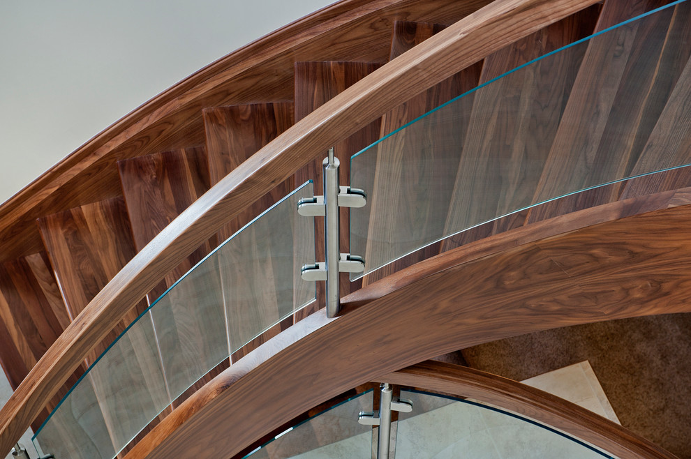 Example of a minimalist wooden curved open and glass railing staircase design in Edmonton