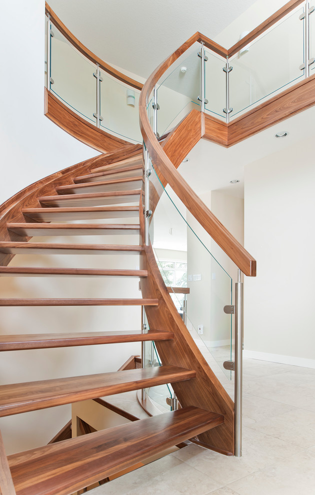 Cette image montre un escalier sans contremarche courbe design avec des marches en bois et un garde-corps en verre.