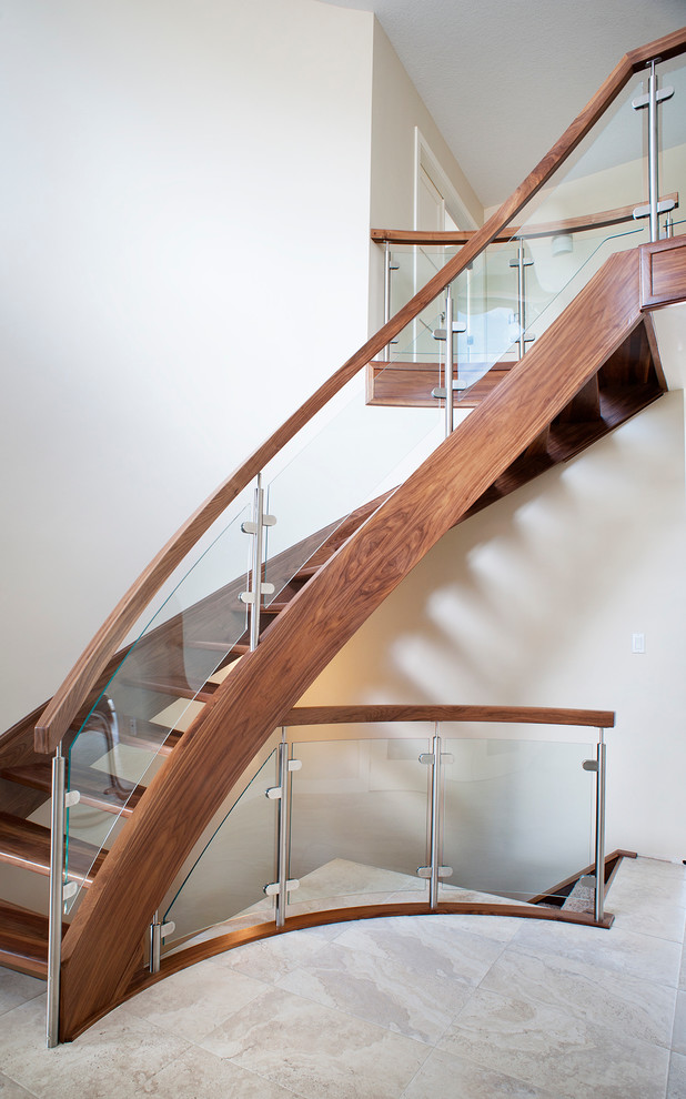 Example of a minimalist wooden curved open and glass railing staircase design in Edmonton
