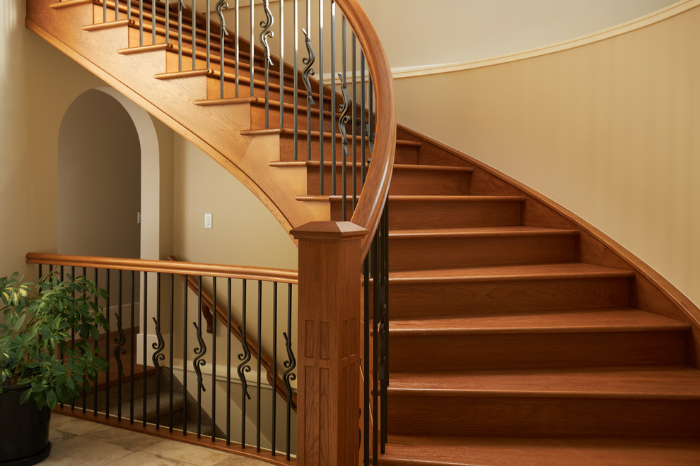 Стильный дизайн: большая изогнутая деревянная лестница в классическом стиле с деревянными ступенями и перилами из смешанных материалов - последний тренд