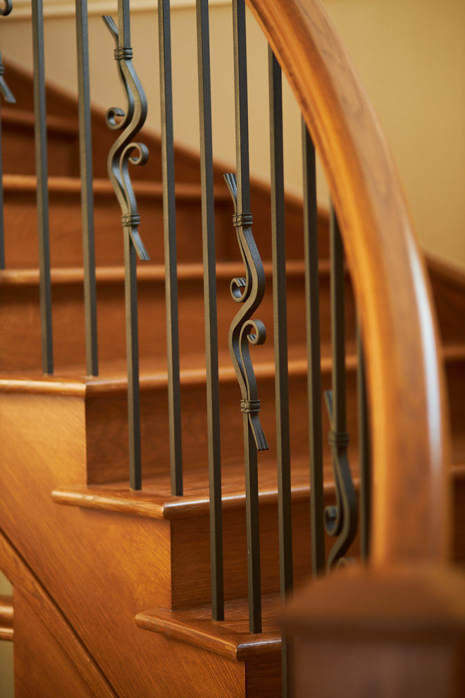 Idée de décoration pour un grand escalier courbe tradition avec des marches en bois, des contremarches en bois et un garde-corps en matériaux mixtes.