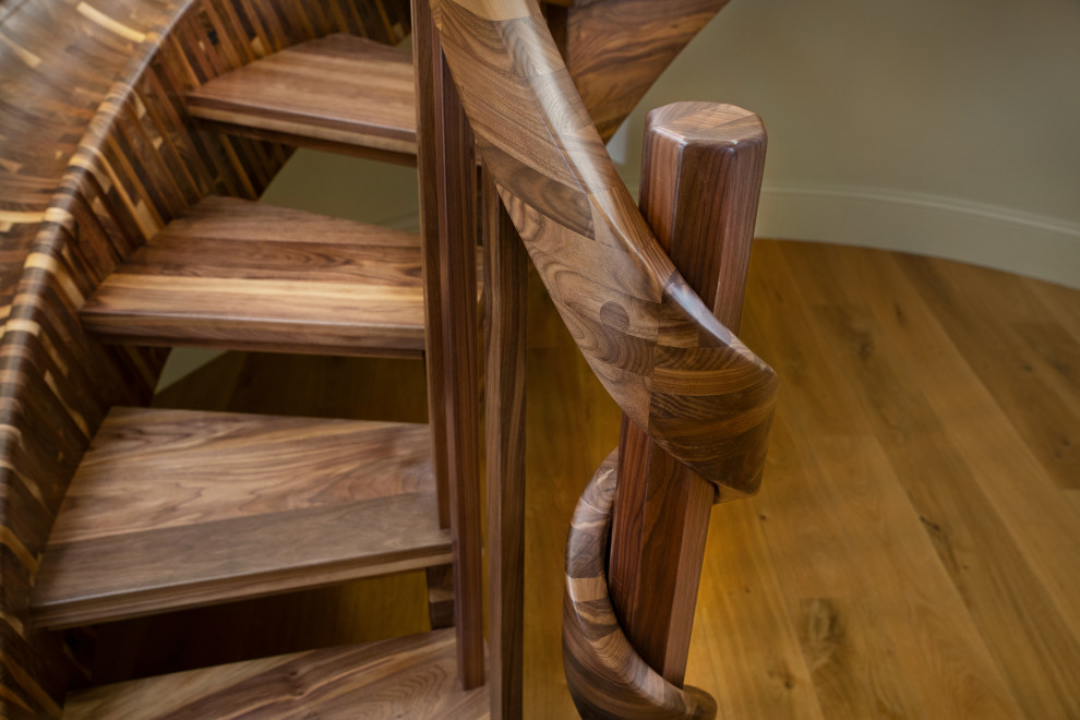Cette photo montre un très grand escalier sans contremarche courbe éclectique avec des marches en bois et un garde-corps en bois.