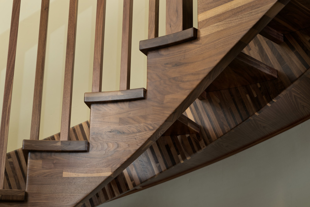 Стильный дизайн: огромная изогнутая лестница в стиле фьюжн с деревянными ступенями и деревянными перилами без подступенок - последний тренд