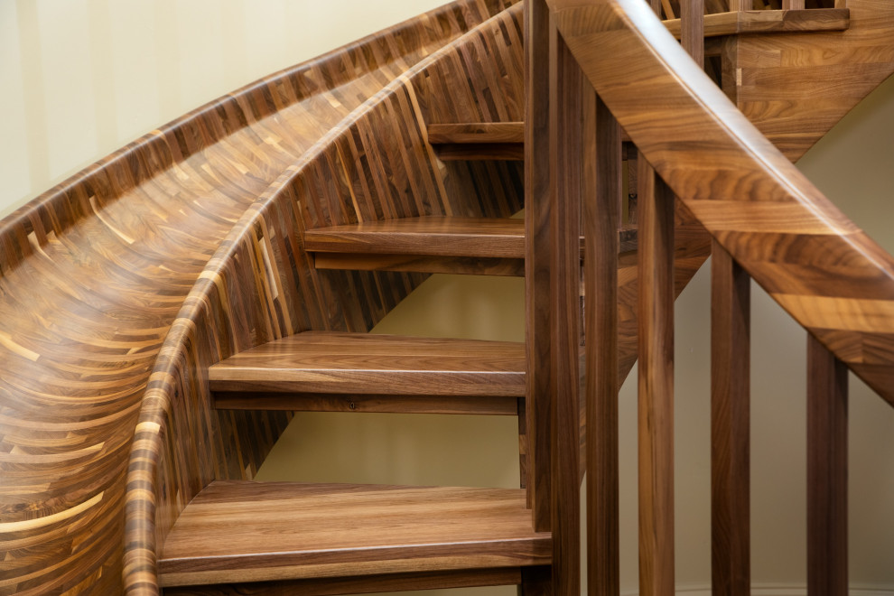 Cette image montre un très grand escalier sans contremarche courbe bohème avec des marches en bois et un garde-corps en bois.