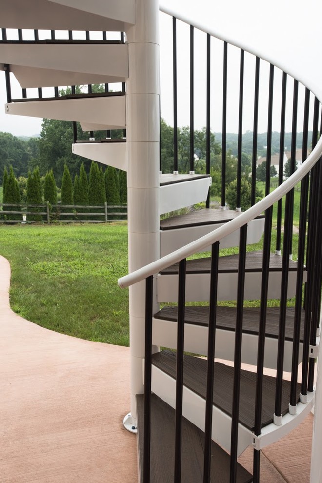 This is an example of a large modern wood spiral metal railing staircase in Philadelphia with metal risers.