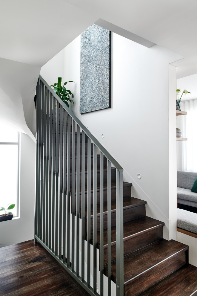 Cette photo montre un grand escalier scandinave en U avec des marches en bois, des contremarches en bois et un garde-corps en métal.