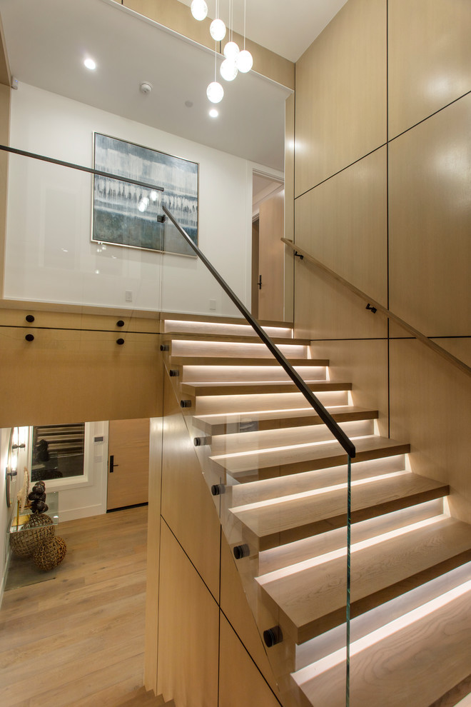Inspiration pour un escalier minimaliste en U de taille moyenne avec des marches en bois, des contremarches en bois, un garde-corps en verre et palier.