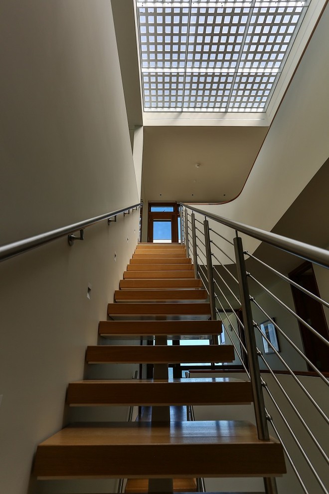 Immagine di una scala a rampa dritta design di medie dimensioni con pedata in legno, nessuna alzata e parapetto in metallo