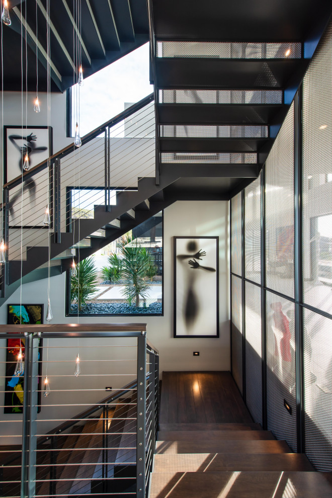На фото: большая п-образная металлическая лестница в современном стиле с деревянными ступенями и перилами из смешанных материалов