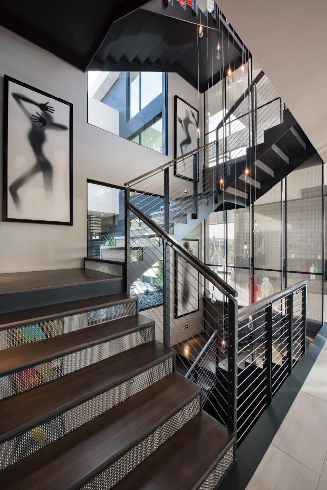 Aménagement d'un grand escalier contemporain en U avec des marches en bois, des contremarches en métal et un garde-corps en matériaux mixtes.