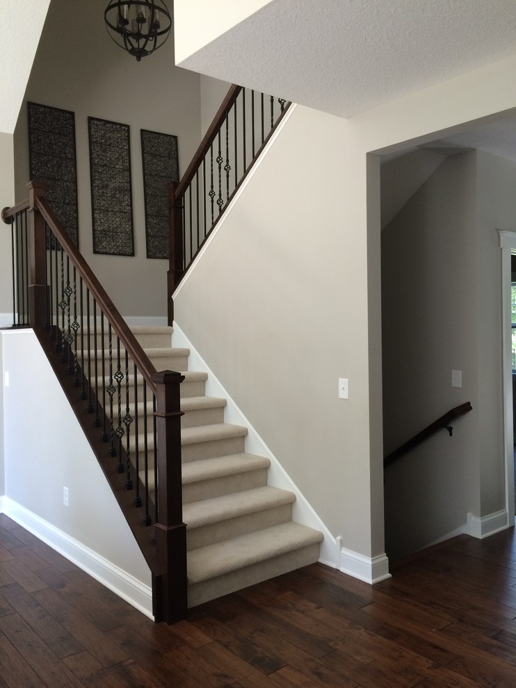 Photo of a large classic carpeted u-shaped mixed railing staircase in Minneapolis with carpeted risers.