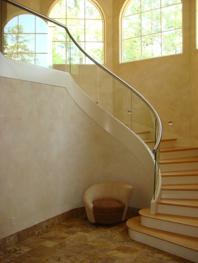 This is an example of a medium sized classic wood curved glass railing staircase in Other with wood risers.