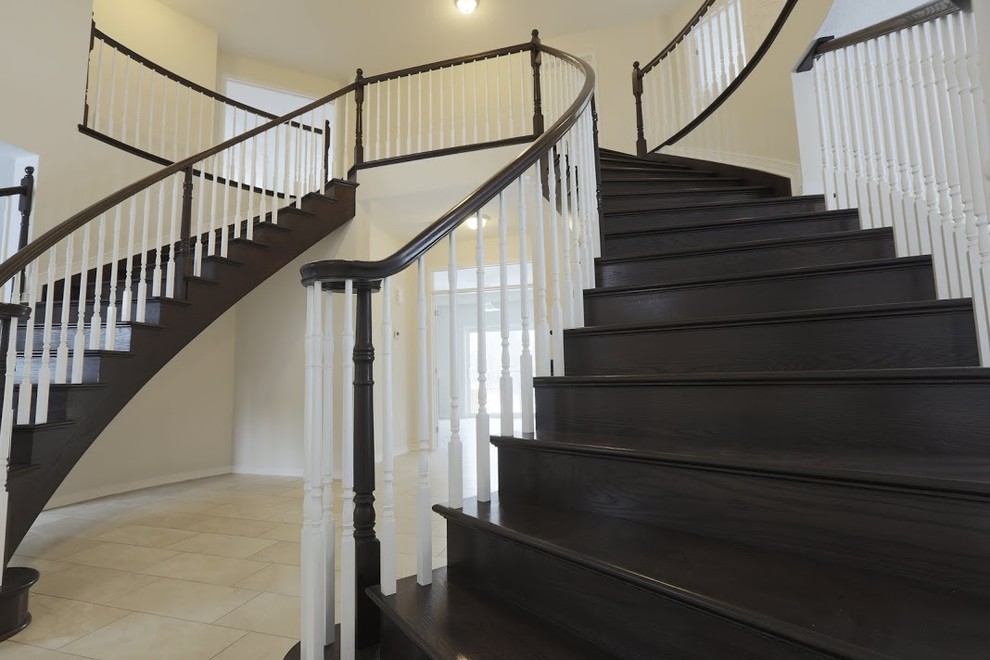 Expansive traditional wood curved staircase in Ottawa with wood risers.