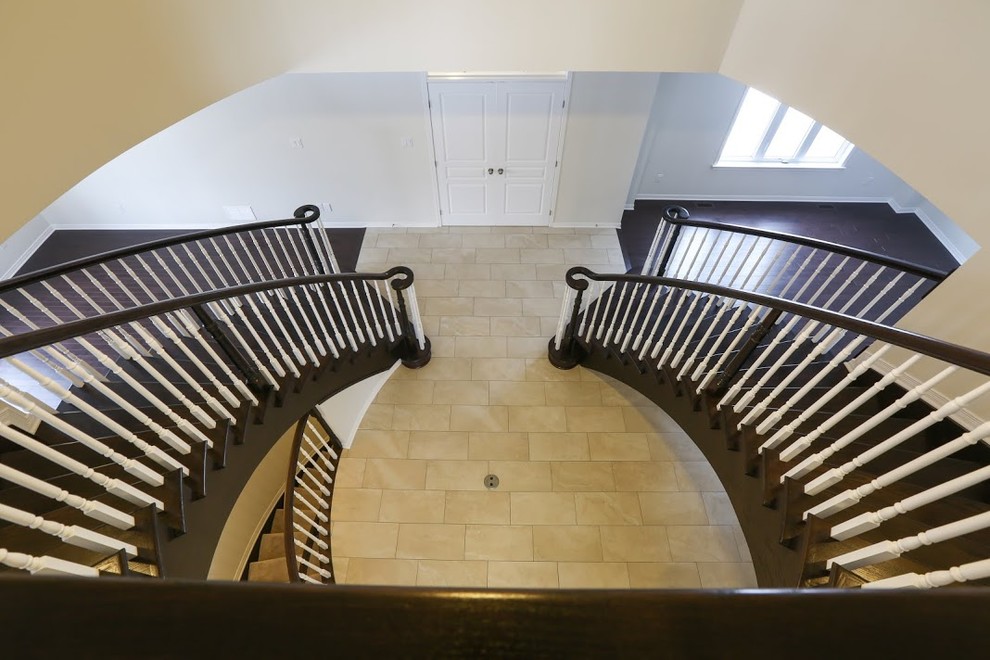 Inspiration pour un très grand escalier courbe traditionnel avec des marches en bois et des contremarches en bois.