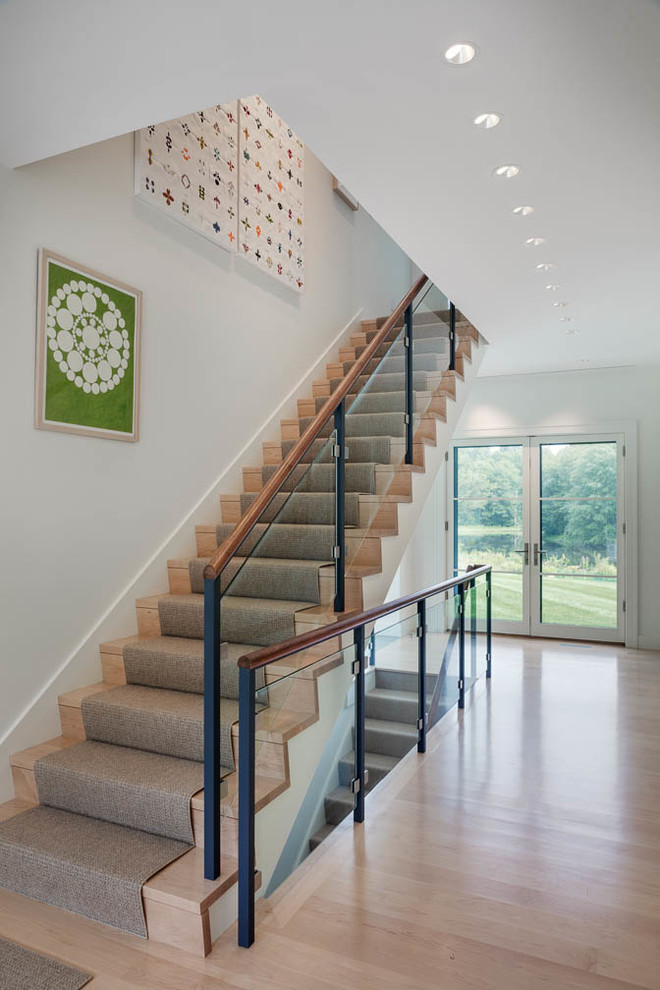 Cette image montre un escalier droit design avec des marches en bois, des contremarches en bois et un garde-corps en verre.