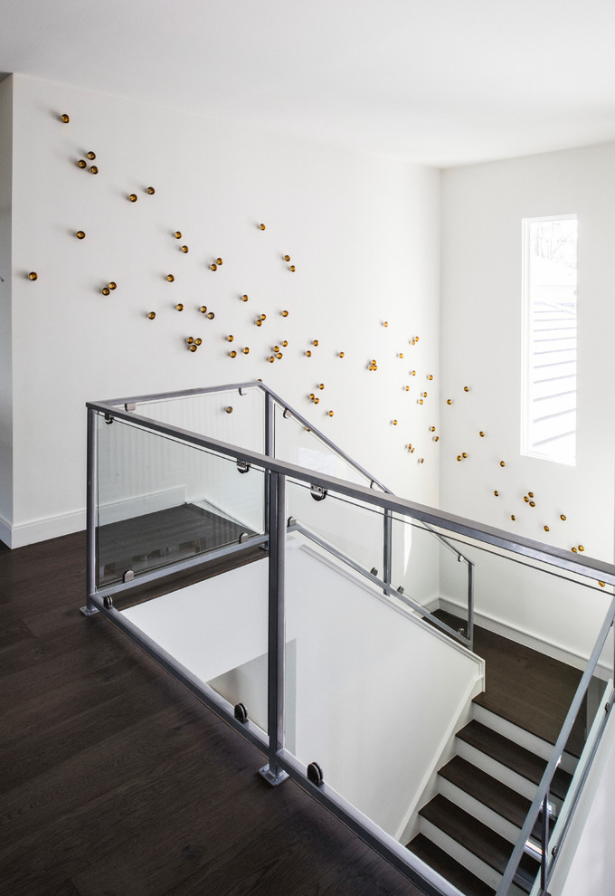 На фото: огромная п-образная лестница в стиле неоклассика (современная классика) с деревянными ступенями, крашенными деревянными подступенками и стеклянными перилами