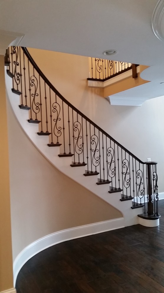 Imagen de escalera curva clásica de tamaño medio con escalones de madera, contrahuellas de madera pintada y barandilla de madera