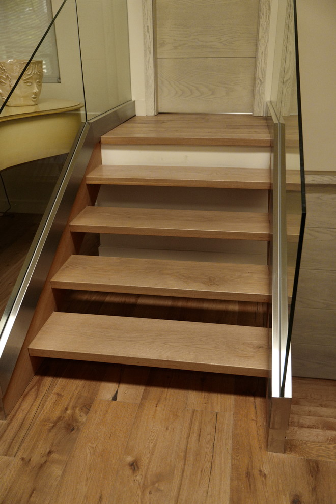Exemple d'un escalier droit tendance avec des marches en bois, des contremarches en bois et un garde-corps en verre.