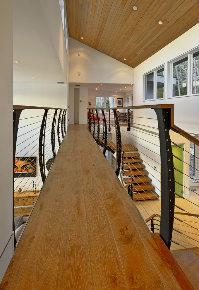 Imagen de escalera suspendida minimalista sin contrahuella con escalones de madera y barandilla de cable