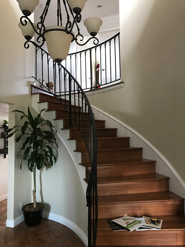 Example of a mid-sized classic wooden curved metal railing staircase design in Orange County with wooden risers