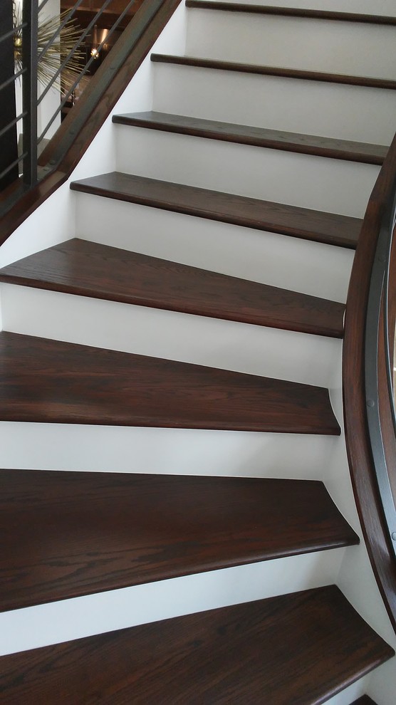 Modelo de escalera curva moderna grande con escalones de madera, contrahuellas de madera pintada y barandilla de metal