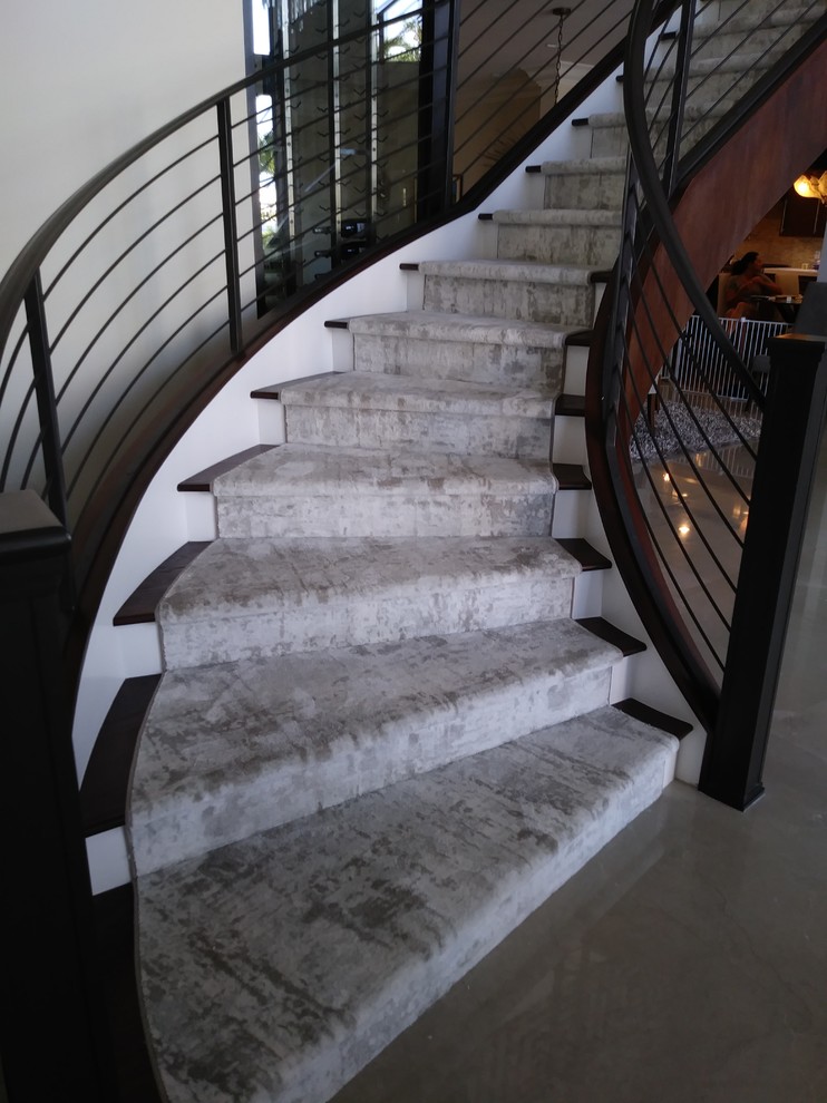 Diseño de escalera curva minimalista grande con escalones de madera, contrahuellas de madera pintada y barandilla de metal