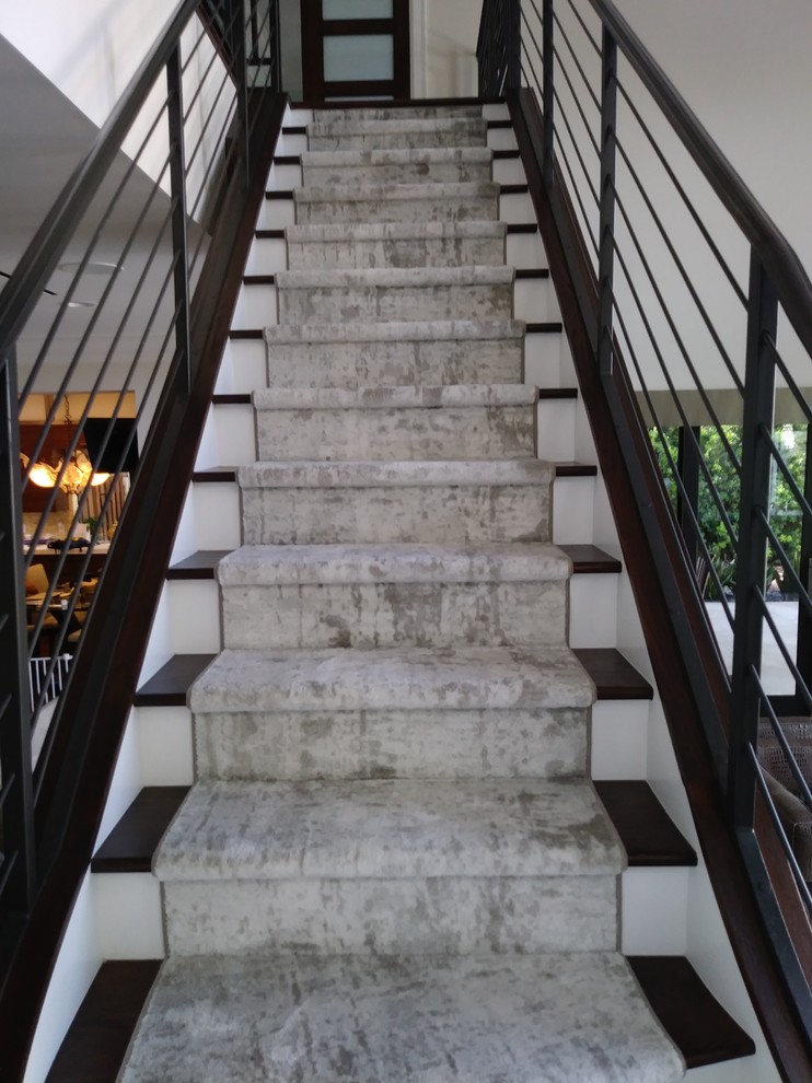 Стильный дизайн: большая изогнутая лестница в стиле модернизм с деревянными ступенями, крашенными деревянными подступенками и металлическими перилами - последний тренд
