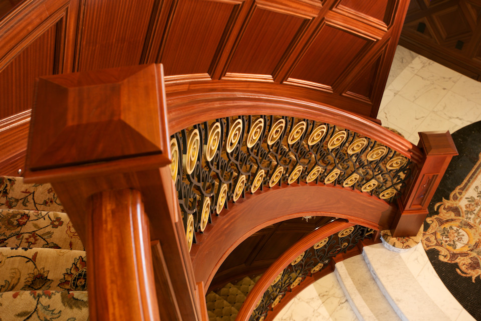 На фото: огромная изогнутая лестница в восточном стиле с ступенями с ковровым покрытием, ковровыми подступенками и перилами из смешанных материалов с