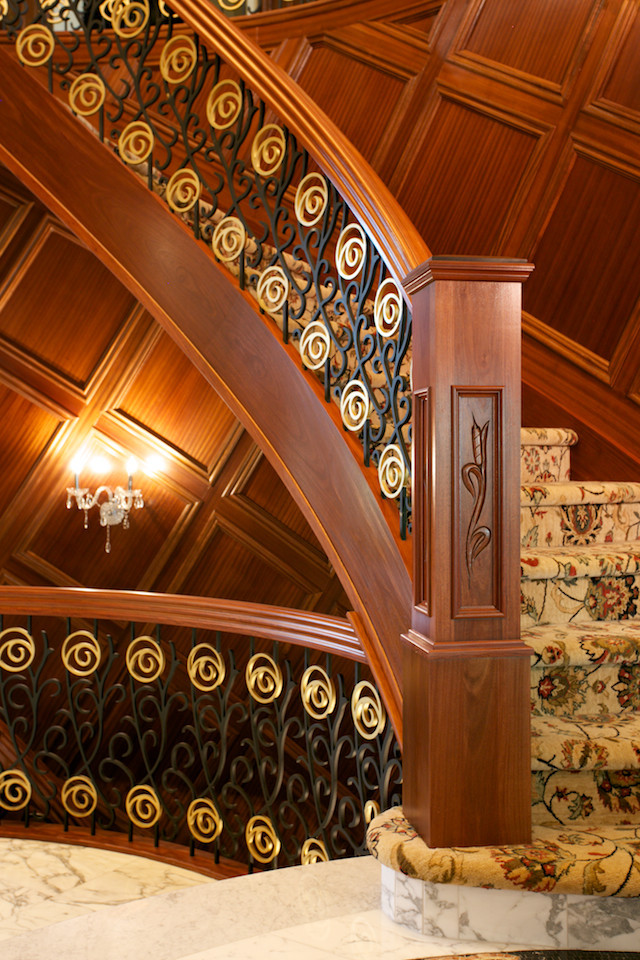 Bild på en mycket stor orientalisk svängd trappa, med heltäckningsmatta, sättsteg med heltäckningsmatta och räcke i flera material