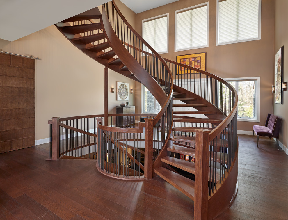 Example of a large transitional wooden curved open and metal railing staircase design in Edmonton