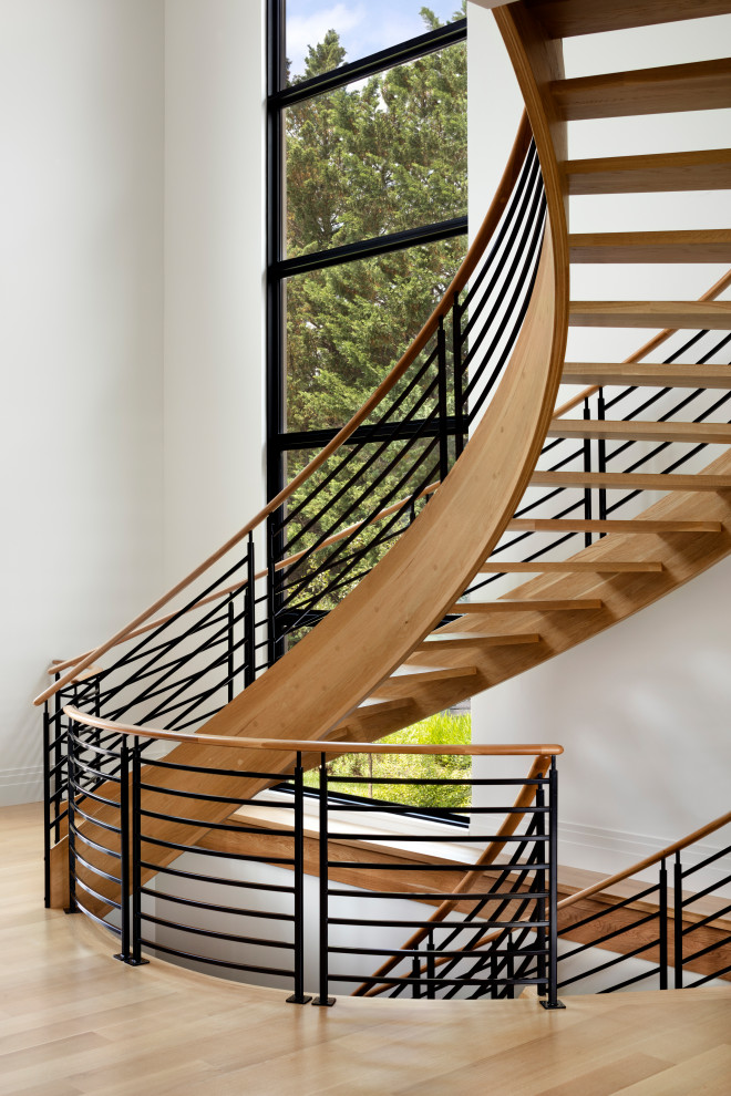 Immagine di un'ampia scala curva moderna con pedata in legno, nessuna alzata e parapetto in legno