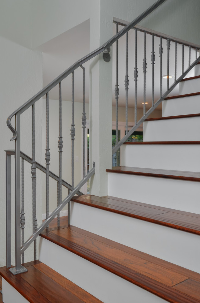 Пример оригинального дизайна: большая прямая лестница в стиле неоклассика (современная классика) с деревянными ступенями и металлическими перилами