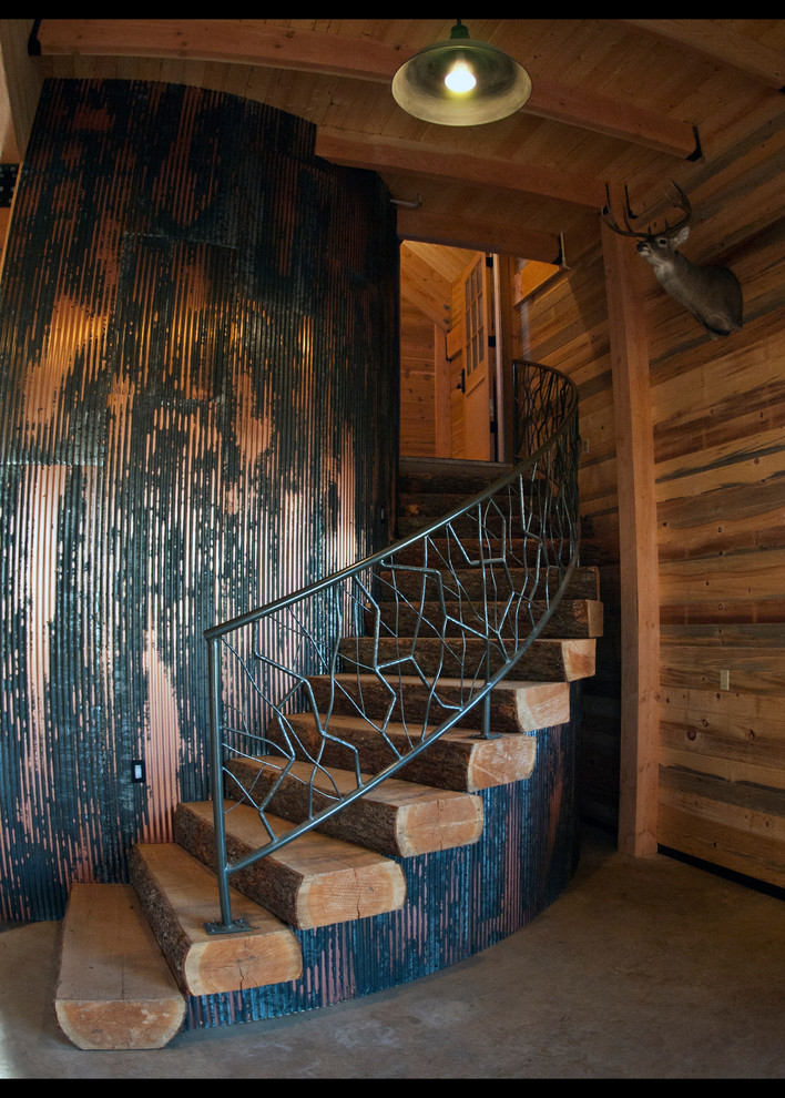 На фото: большая изогнутая деревянная лестница в стиле рустика с деревянными ступенями