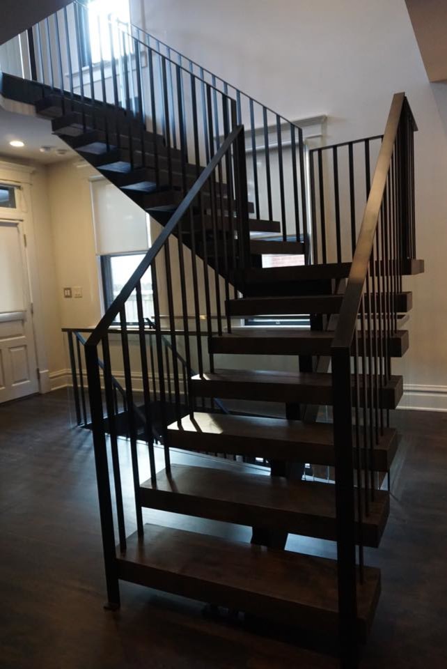 Cette image montre un grand escalier minimaliste en L avec des marches en bois et des contremarches en métal.