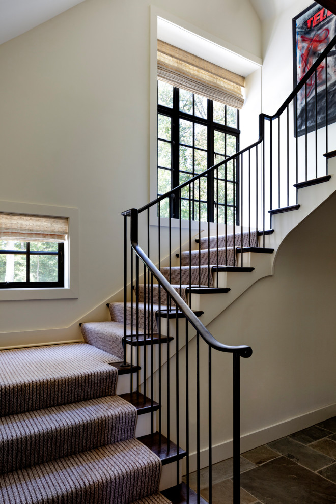Imagen de escalera en L clásica de tamaño medio con escalones de madera, contrahuellas enmoquetadas y barandilla de metal