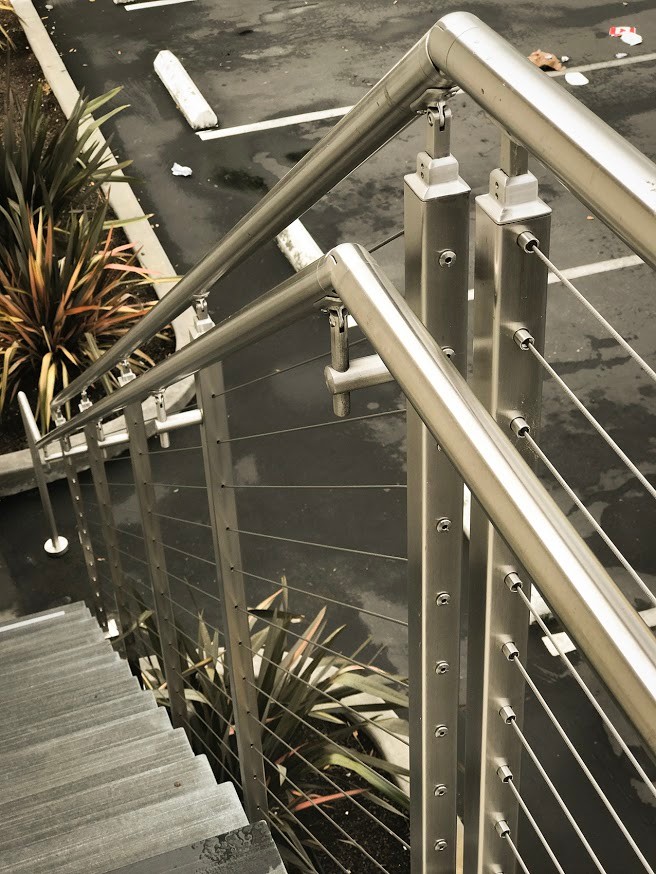 На фото: большая прямая металлическая лестница в стиле модернизм с перилами из тросов