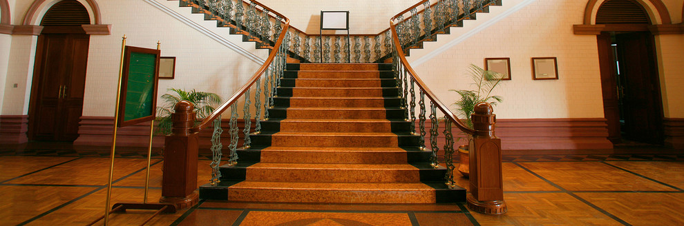 Идея дизайна: большая изогнутая лестница в викторианском стиле с крашенными деревянными ступенями и крашенными деревянными подступенками