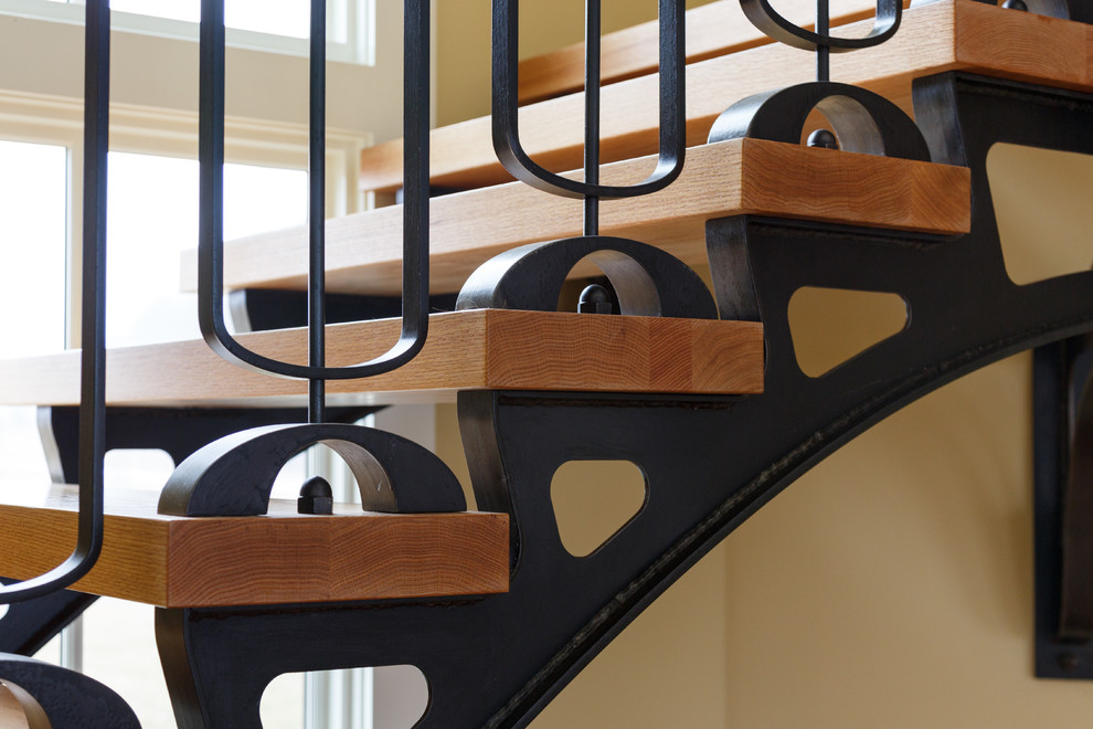 Пример оригинального дизайна: большая изогнутая лестница в современном стиле с деревянными ступенями и металлическими перилами без подступенок
