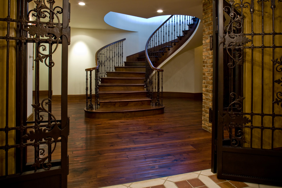 На фото: большая изогнутая деревянная лестница в классическом стиле с деревянными ступенями с